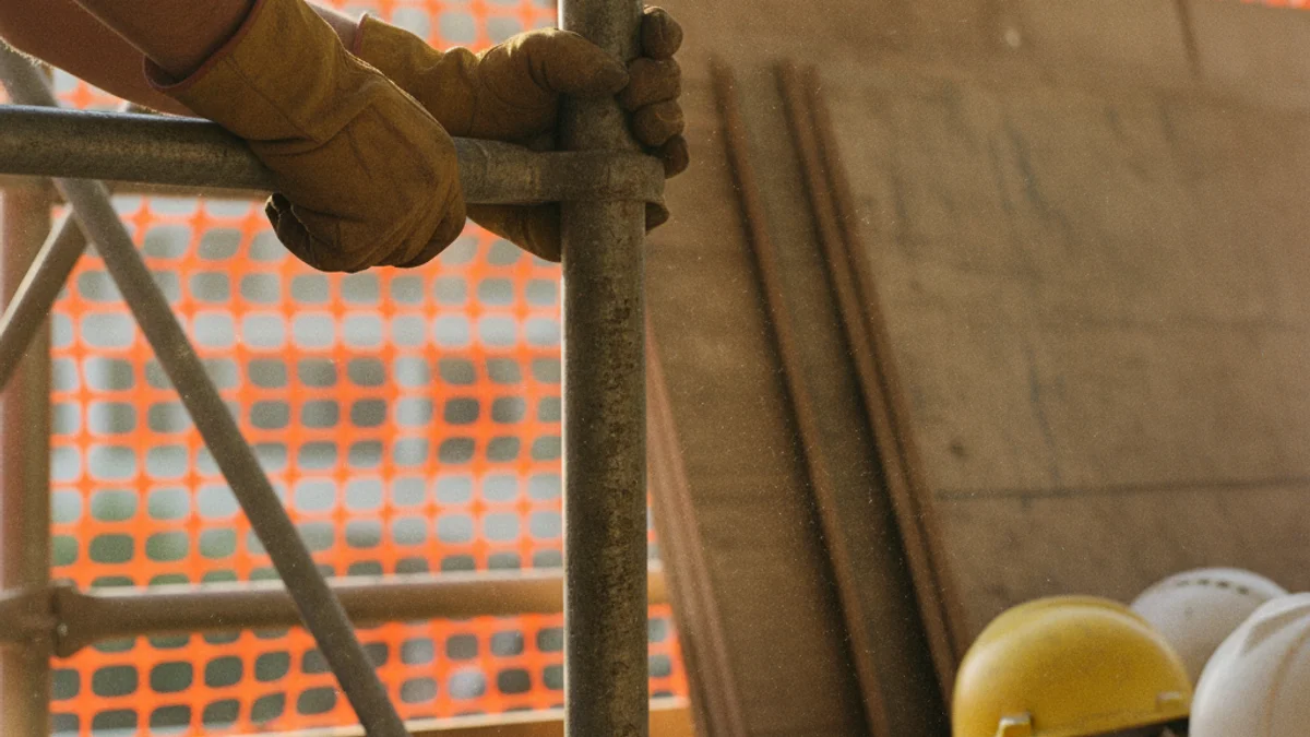 Worker gripping scaffolding pipe at a construction site